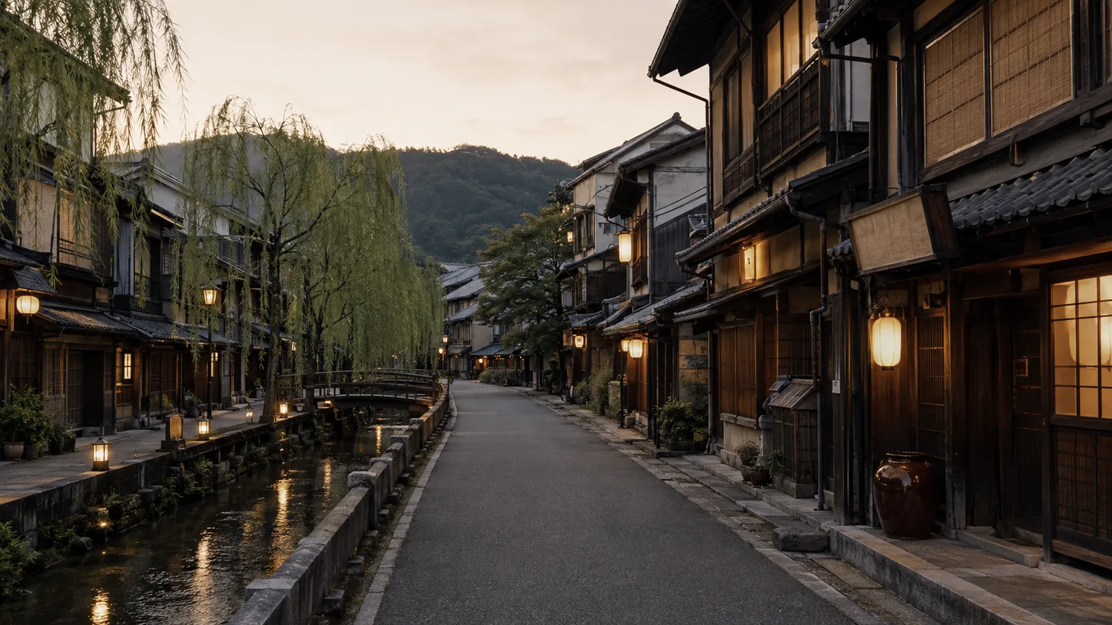 A traditional hot-spring town street at dusk, lined with wooden ryokan buildings and warmly lit lanterns